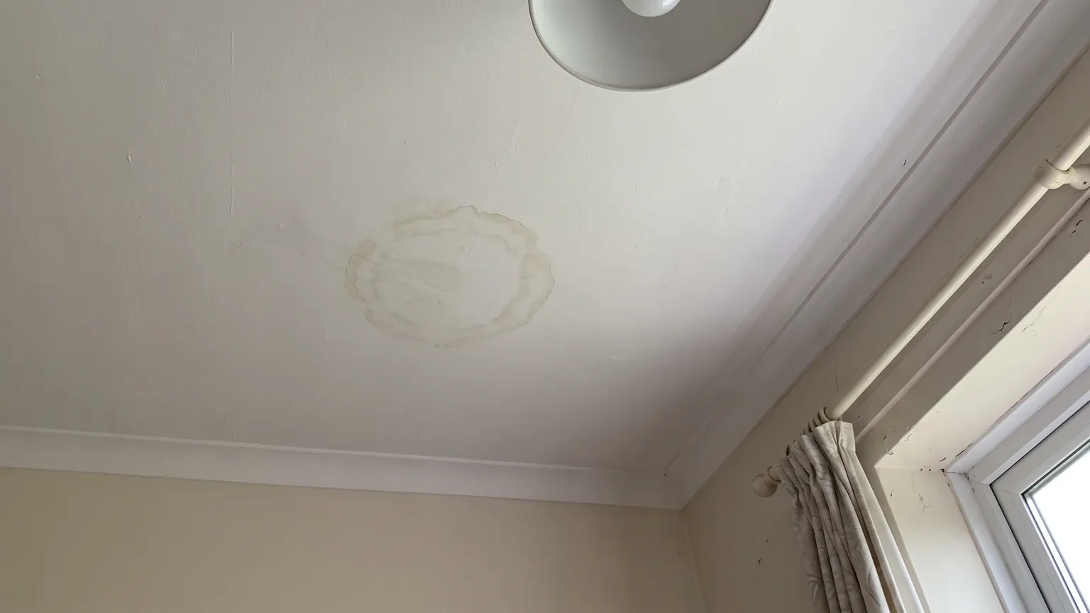 Bedroom ceiling with an old dry ringed tan water stain on white paint