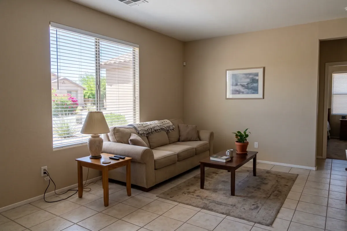 An ordinary bright living room in a Phoenix home with tile flooring and nothing visibly wrong with the walls or ceiling