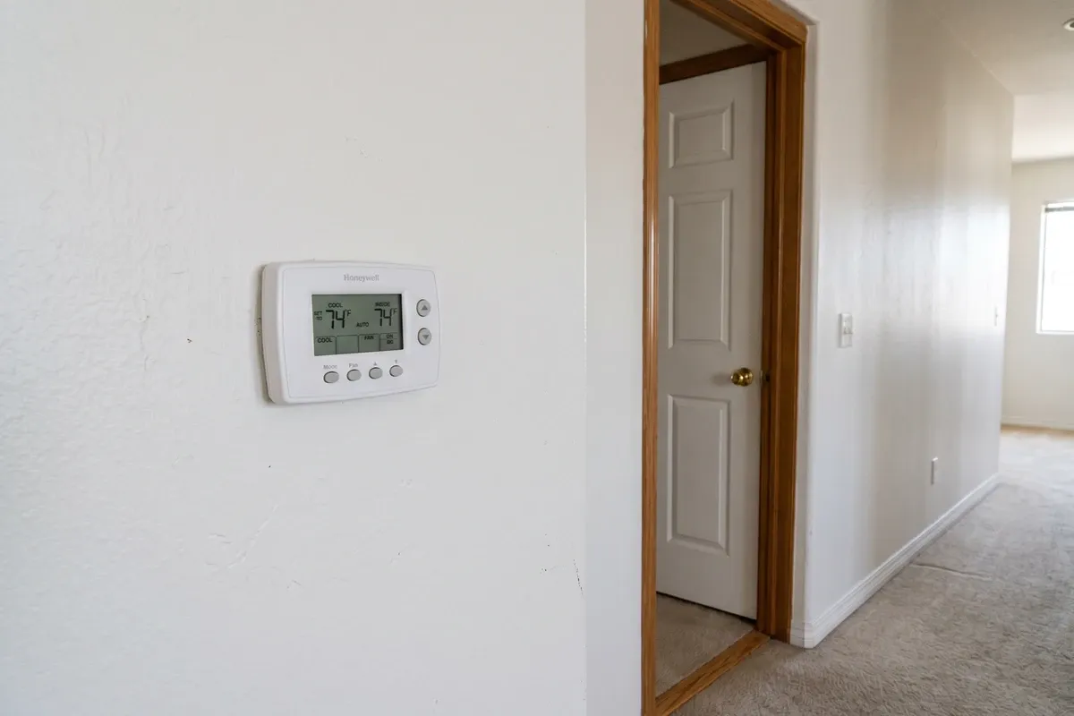 Residential wall thermostat in a Phoenix home hallway, white painted walls, normal interior setting, no people
