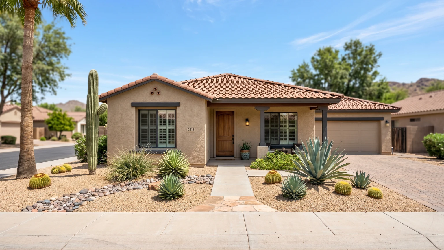 A single-story Phoenix home with tan stucco, a clay-tile roof, and low-water desert landscaping under a clear blue sky.